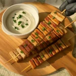 Fit tortilja kebab ražnjići od integralnih tortilja i piletine, posluženi na drvenoj dasci uz jogurt umak i svježi peršin