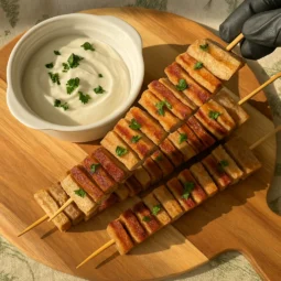 Fit tortilja kebab ražnjići od integralnih tortilja i piletine, posluženi na drvenoj dasci uz jogurt umak i svježi peršin