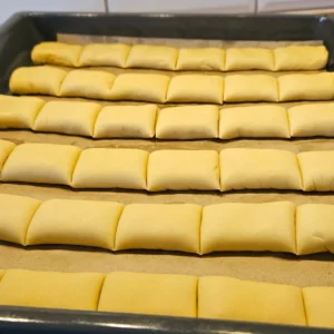 Narezane štrudlice s pekmezom složene u pleh na papir za pečenje – priprema prije pečenja domaćih kolačića