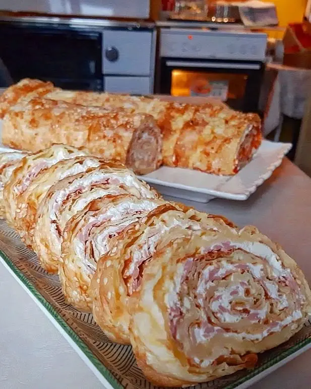 Narezani brzi slani rolat sa šunkom i ajvarom na bijelom tanjiru