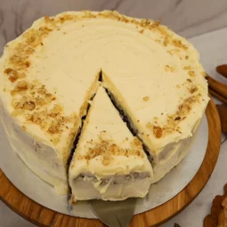 Začinjena torta od jabuka s kremom od sira i cimetom, ukrašena orasima, poslužen komad na tanjiru