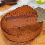 Komad čokoladne mousse torte na metalnoj lopatici, s bogatim čokoladnim slojem i finim posipom od kakaa