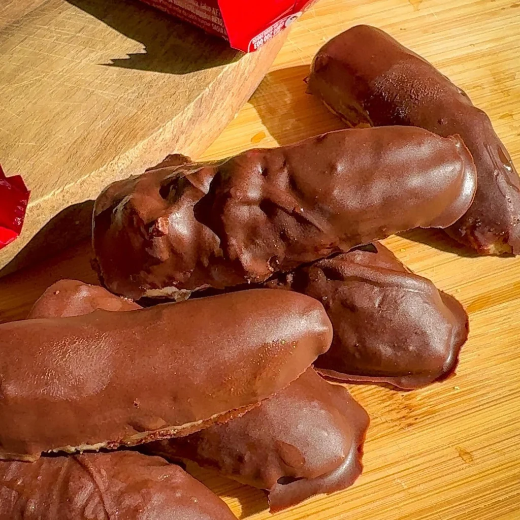 Komad domaće krem bananice u ruci prikazuje mekani unutrašnji dio obložen čokoladom