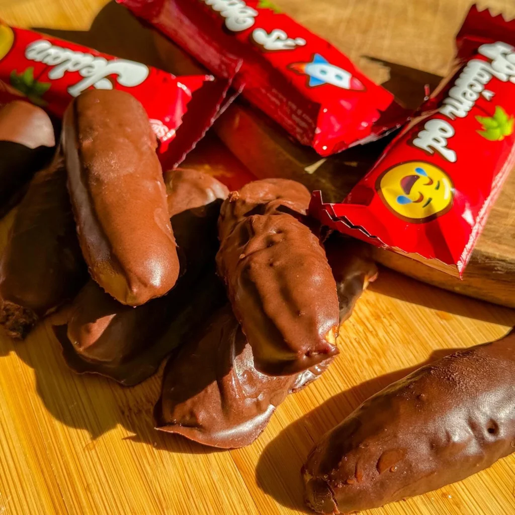 Domaće krem bananice pored kupovnih čokoladnih bananica na drvenoj dasci