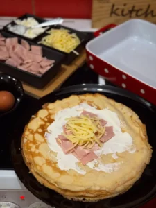 Mazanje palačinke pavlakom i slaganje šunke i sira prije motanja